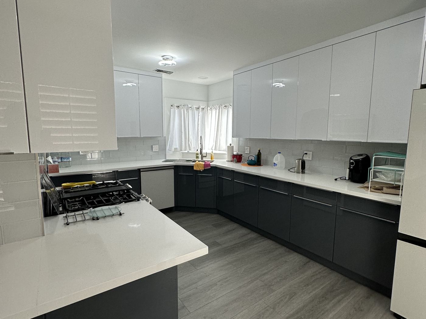 The modernized kitchen with high-gloss white and charcoal cabinetry, quartz counters, and new flooring