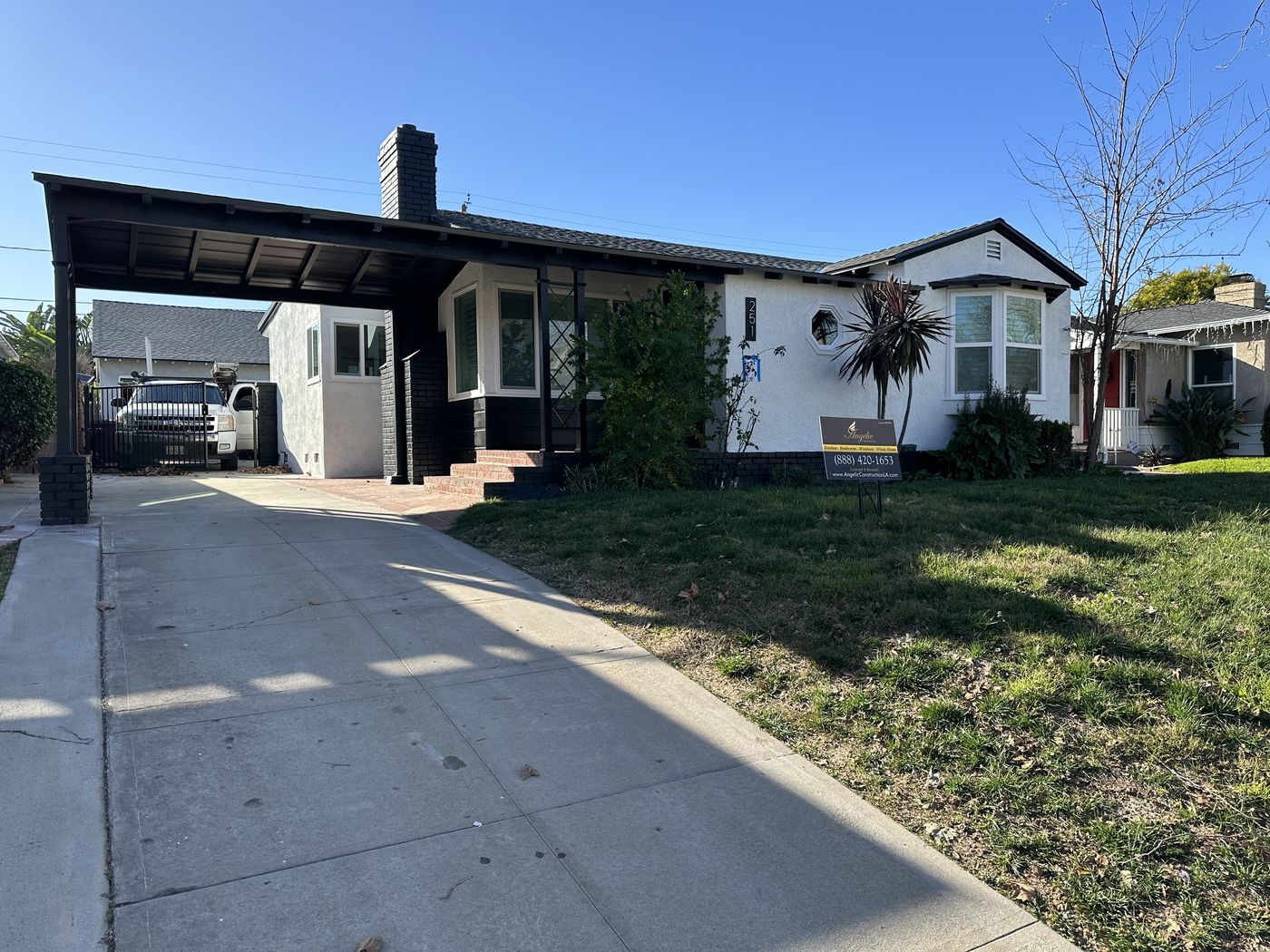 The same home after a complete exterior remodel with crisp white stucco, black trim, new windows, and a rebuilt carport